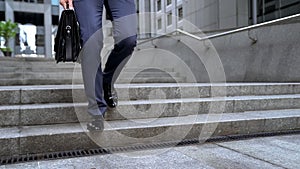 Businessman walking downstairs holding briefcase, going to important meeting