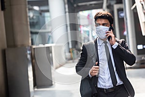 Businessman walking in an empty city during covid-19 outbreak make phone call and wearing mask