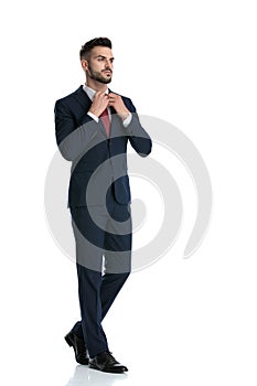 Businessman walking while fixing his tie with cool attitude