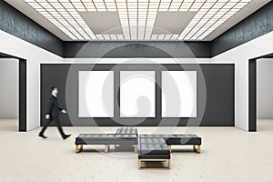 Businessman walking in gallery interior with three empty posters
