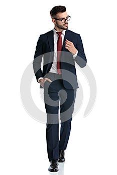 Businessman walking with hand in pocket and looking aside cool