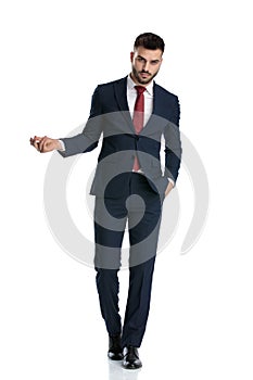 Businessman walking with hand in pocket and snapping fingers serious