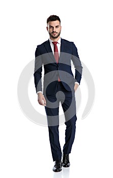 Businessman walking with hand in pocket and striking a pose