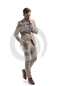 Businessman walking on his way, looking down, fixing his collar