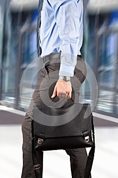 Businessman walking and holding a leather briefcase in his han