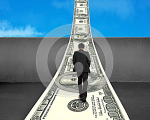 Businessman walking on money way over concrete wall