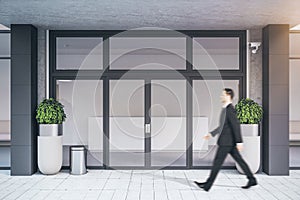 Businessman walking near contemporary entrance to business center