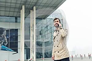 Businessman Walking near the Modern Airport. Looking at his Smartphone Screen