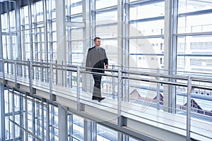 Businessman Walking By Railing In Modern Office