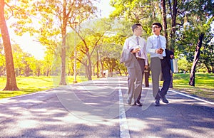 Businessman,They are walking on road in park.They are talking  business.