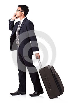 Businessman walking with suitcase and using smartphone