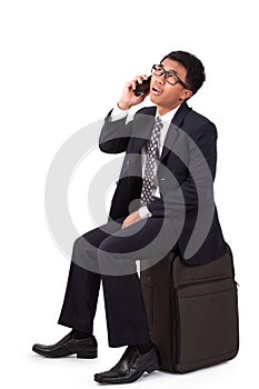 Businessman walking with suitcase and using smartphone