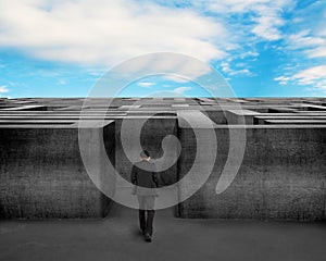 Businessman walking toward to 3D concrete Maze with blue sky