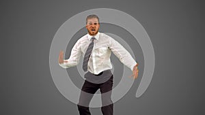 Businessman walking towards camera and dancing funnily on grey background