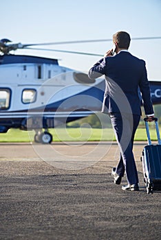 Businessman Walking Towards Helicopter Whilst Talking On Mobile