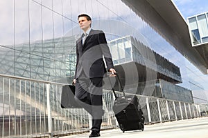 Businessman walking with trolley and bag
