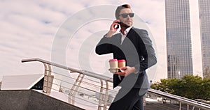 Businessman walking up the stairs with coffee and talking on the phone