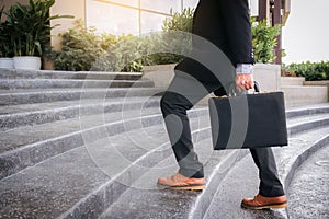 Businessman walking up the stairs and holding a briefcase in han