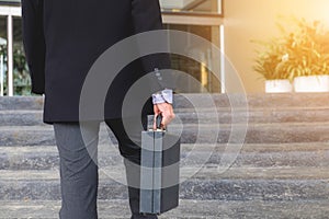 Businessman walking up the stairs and holding a briefcase in han