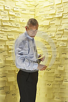 Businessman By Wall Covered In Sticky Notes