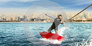 Businessman on water skis in umbrella