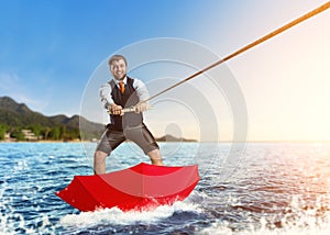 Businessman on water skis in umbrella