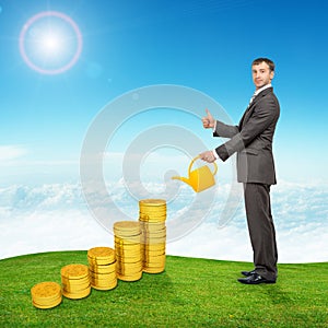Businessman watering coins and showing ok