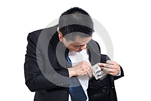 A businessman wear black suit putting money in his pocket isolated on white background.