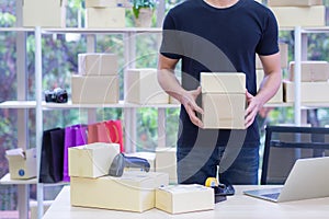 Businessman wearing black t-shirts holding parcel box while standing in the office. Space for text. Business e-commerce concept