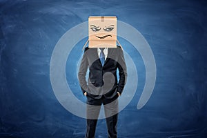 Businessman wearing cardboard box with drawn frowning face on his head