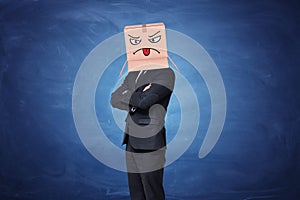 Businessman wearing carton box with painted angry face showing tongue on it