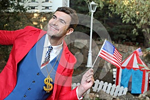 Businessman wearing dollar sign necklace holding US flag