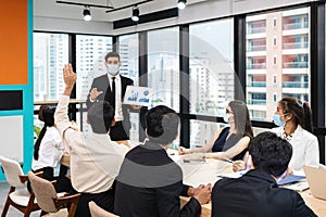 Businessman wearing face mask with presentation of business plan on laptop, corporate business meeting in modern office