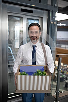 Businessman wearing formal clothing holding box with personal things