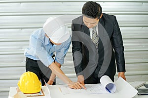 The businessman wearing formal suit talked to the engineer wearing safety hard hat and look