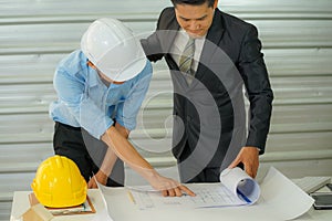 The businessman wearing formal suit talked to the engineer wearing safety hard hat and look