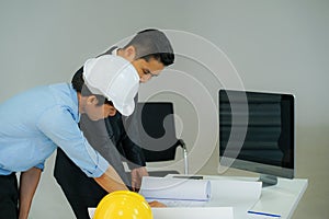 The businessman wearing formal suit talked to the engineer wearing safety hard hat and look