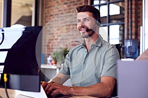 Businessman Wearing Headset At Computer In Customer Support Centre