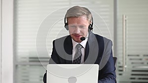 Businessman wearing headset talking making video call on laptop