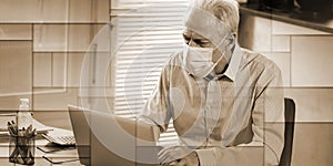 Businessman wearing medical face mask and working on laptop from home, geometric pattern