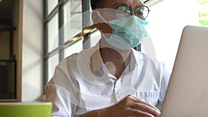 Businessman wearing protective face mask working using his computer laptop.