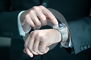 Businessman wearing smart watch with banking, finance or business report app. Man in suit using wearable gadget for work.