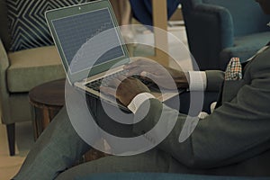 Businessman wearing suit holding laptop on his lap and looking into banking charts