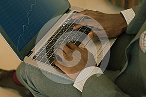 Businessman wearing suit holding laptop on his lap and looking into banking charts