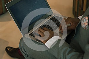 Businessman wearing suit holding laptop on his lap and looking into banking charts