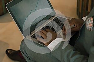 Businessman wearing suit holding laptop on his lap and looking into banking charts