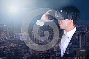 Businessman wearing virtual reality goggles and night city view