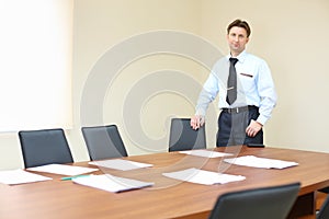 Businessman wearing white shirt stands near table