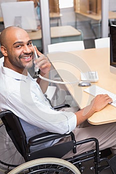 Businessman in wheelchair phoning and smiling at camera