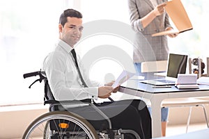 Businessman in wheelchair working with documents in office